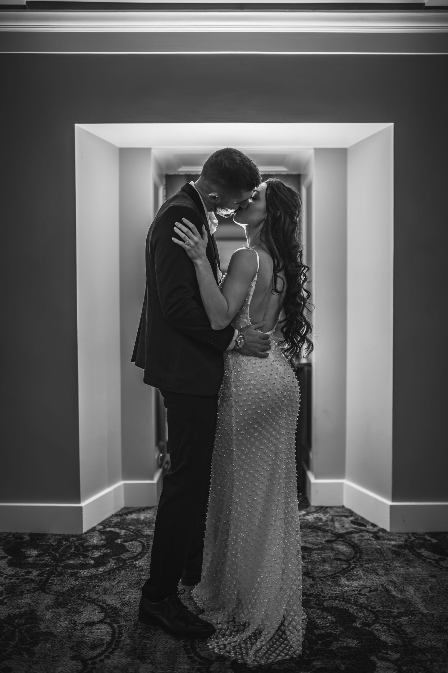 A romantic black and white series of photos showing a couple dancing in an elegant hallway with patterned carpet.