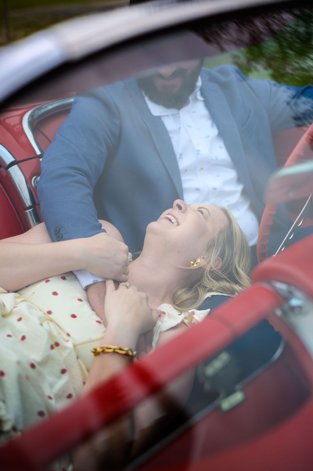 A woman sleeps peacefully while leaning back in the passenger seat of a car wearing a polka dot dress.