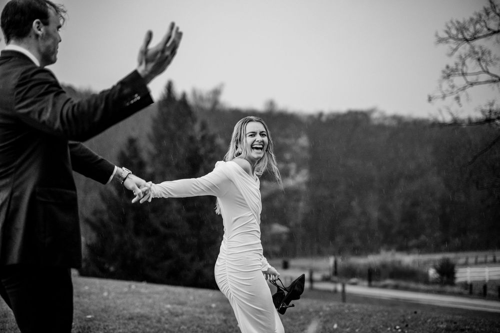 Black and white photo of a joyful bride and groom sharing an emotional moment outdoors in a natural setting.