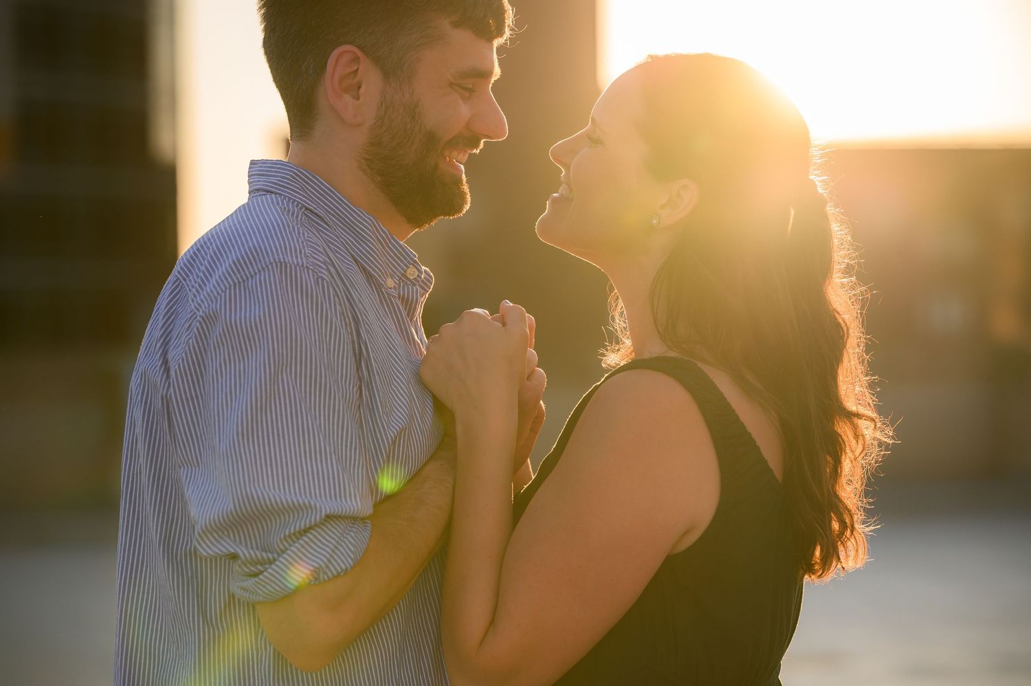 A silhouetted couple shares an intimate moment at sunset with warm golden light surrounding them.