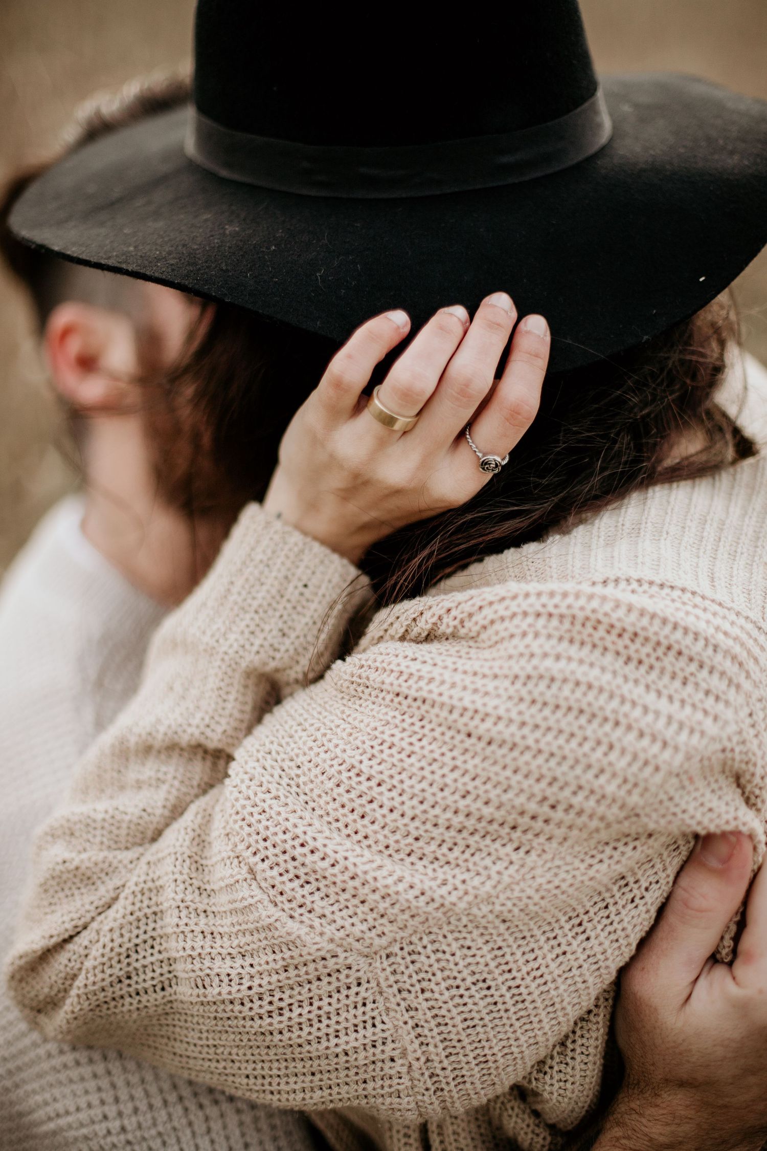 intimate moment with woman sitting on man’s lap, hand on hat, captured from behind