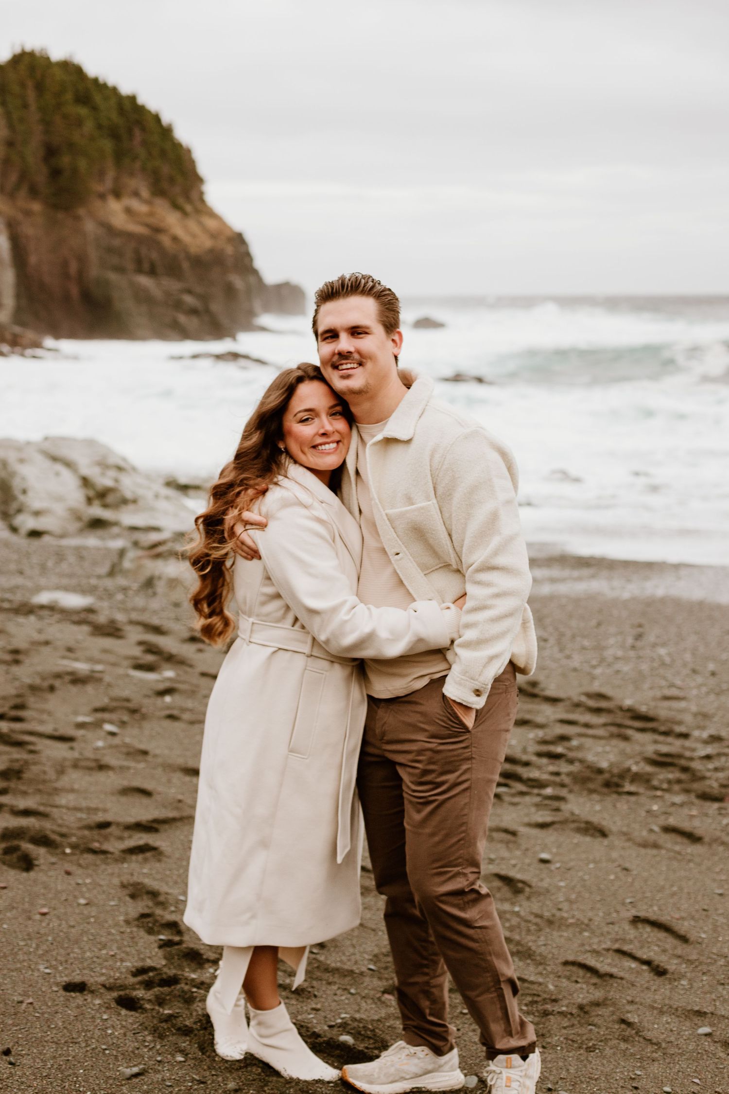 engaged couple hugging and laughing on a beach
