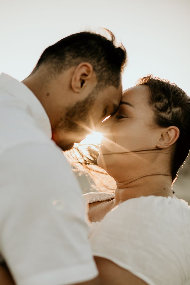 engaged couple resting foreheads with sunset peaking through them