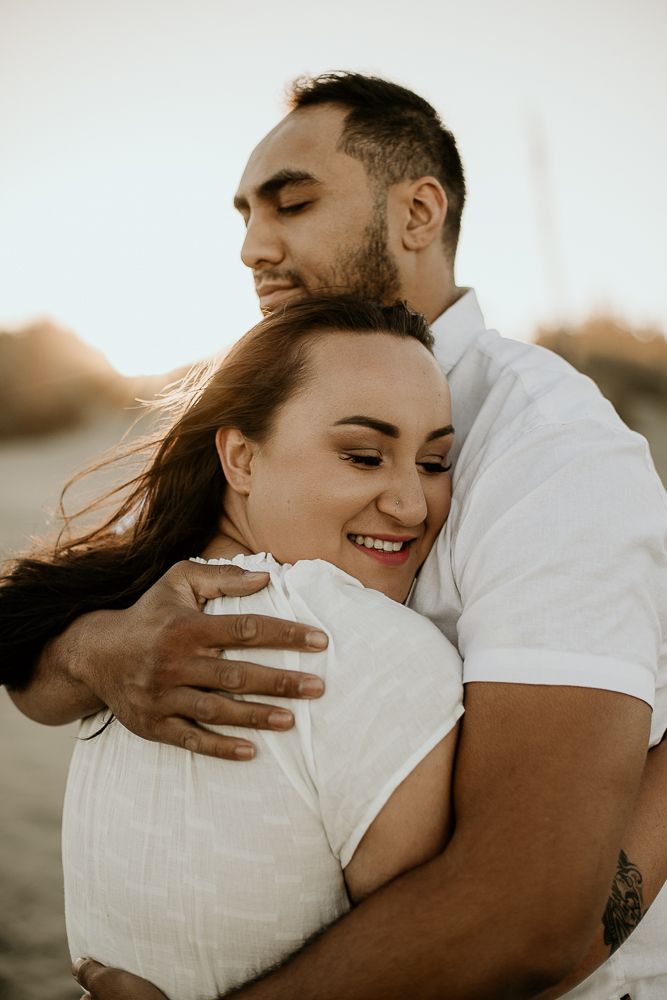 newly engaged couple embracing in a hug with their eyes closed