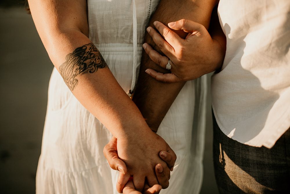 newly engaged couple's holding hands during golden hour on the beach