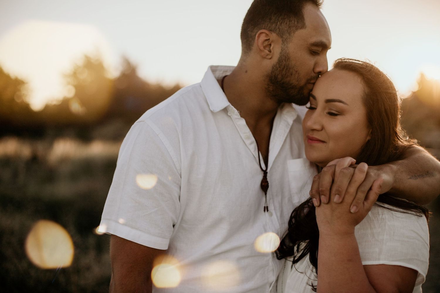 man kissing woman's forehead with his arm wrapped around her