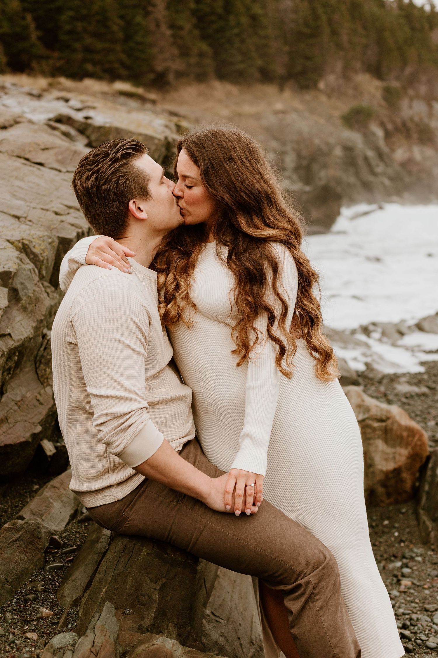 engaged couple kissing by the rocks on a beach in Newfoundland