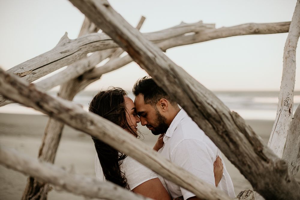 engaged couple foreheads touching intimately on the beach