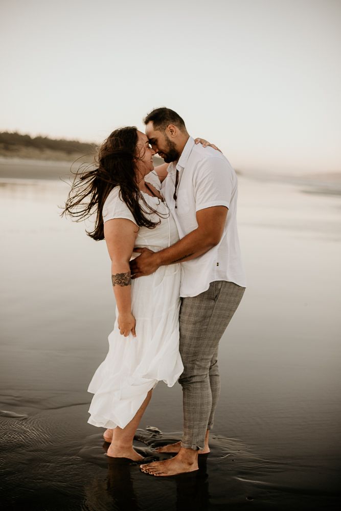 engaged couple hugging and about to kiss on sunset Newfoundland beach