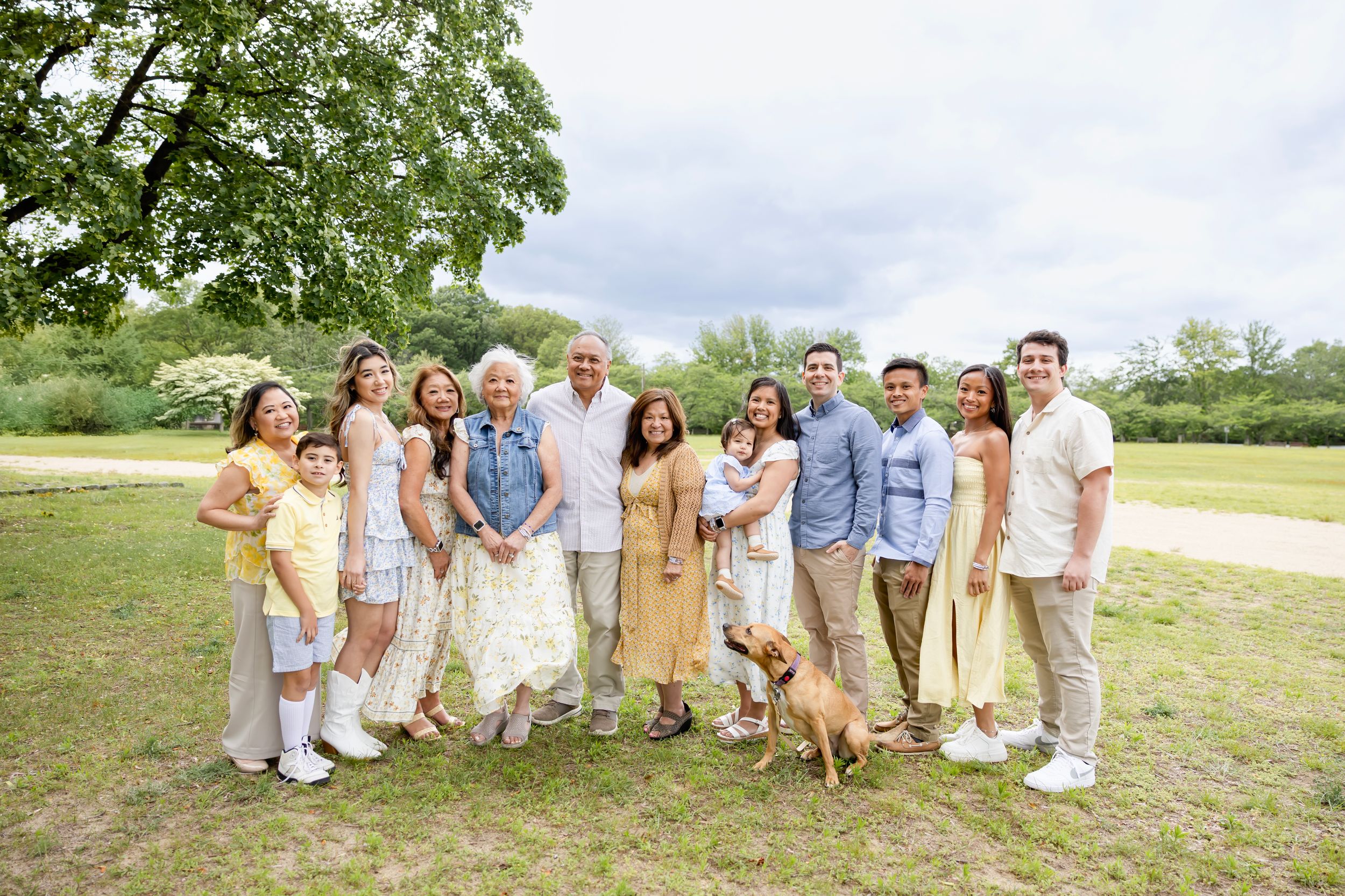 Extended Family Session in coordinated neutral outfits poses together on grass field during outdoor photo session. Family NJ photographer