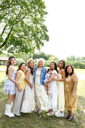 Family Photo Session dressed in light summer outfits standing together outdoors under a large leafy tree. Family NJ photographer
