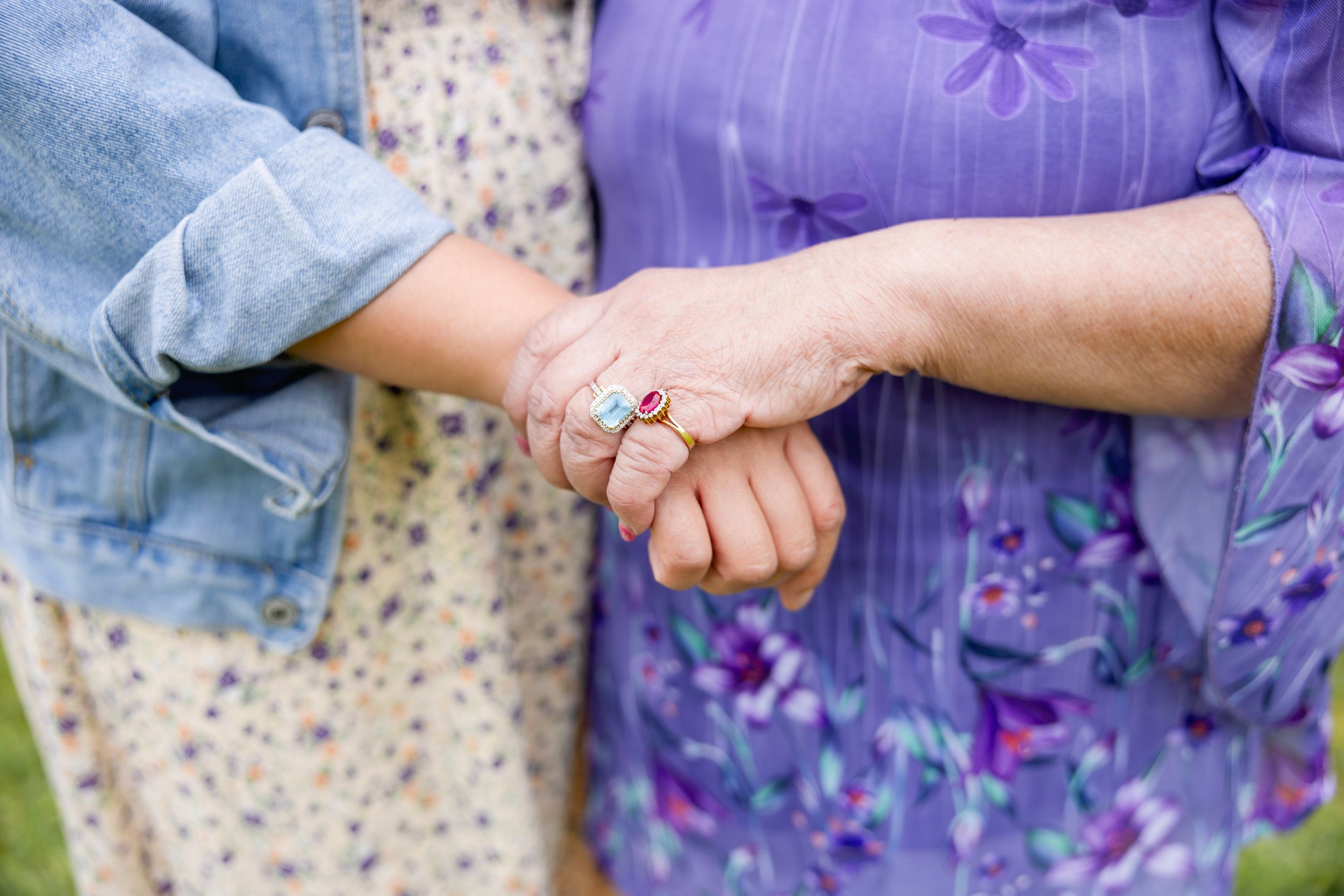 A close-up of hands gently holding purple lavender flowers against a textured neutral background. Family NJ photographer