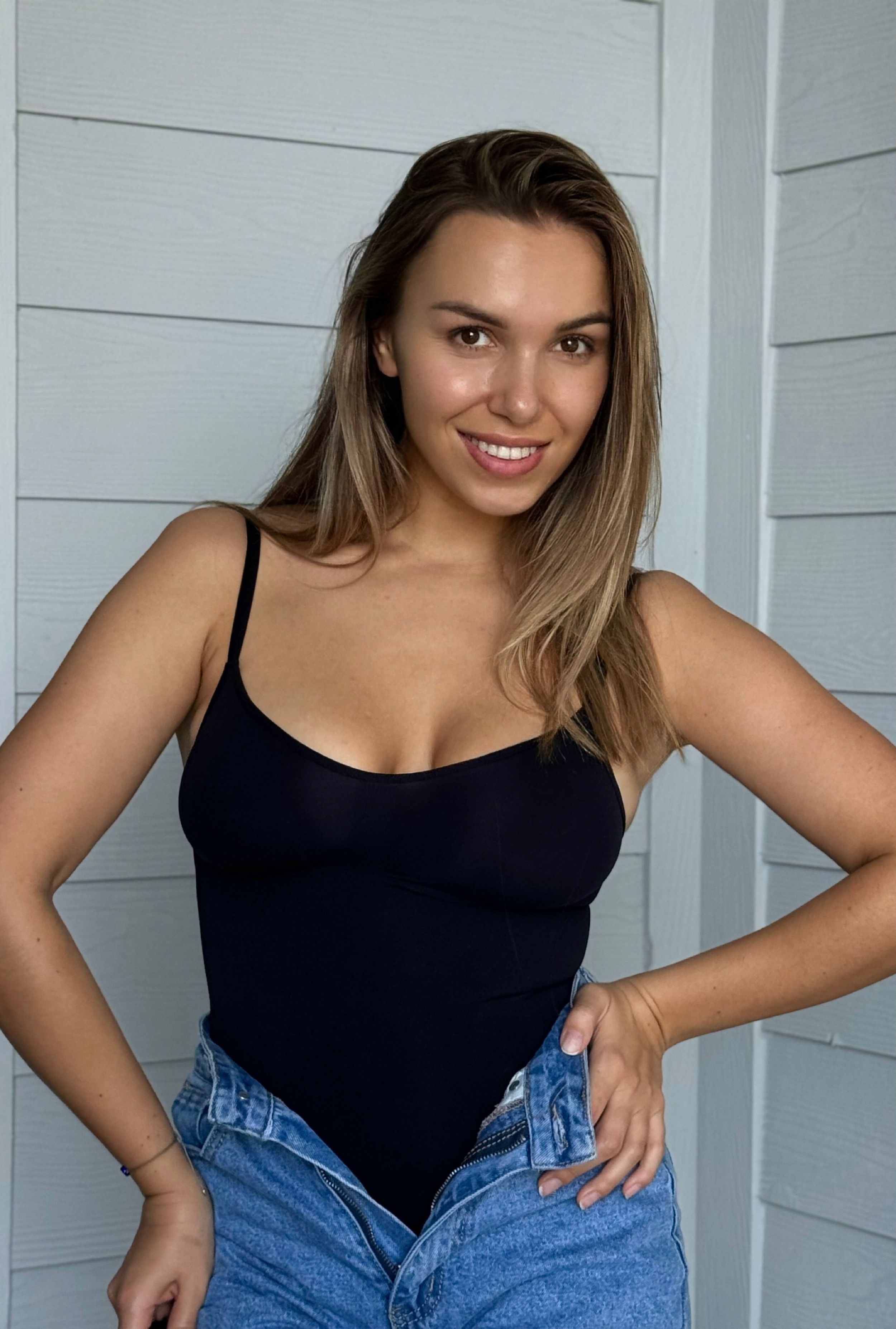 Editorial-style portrait - stylish woman posing near white wall