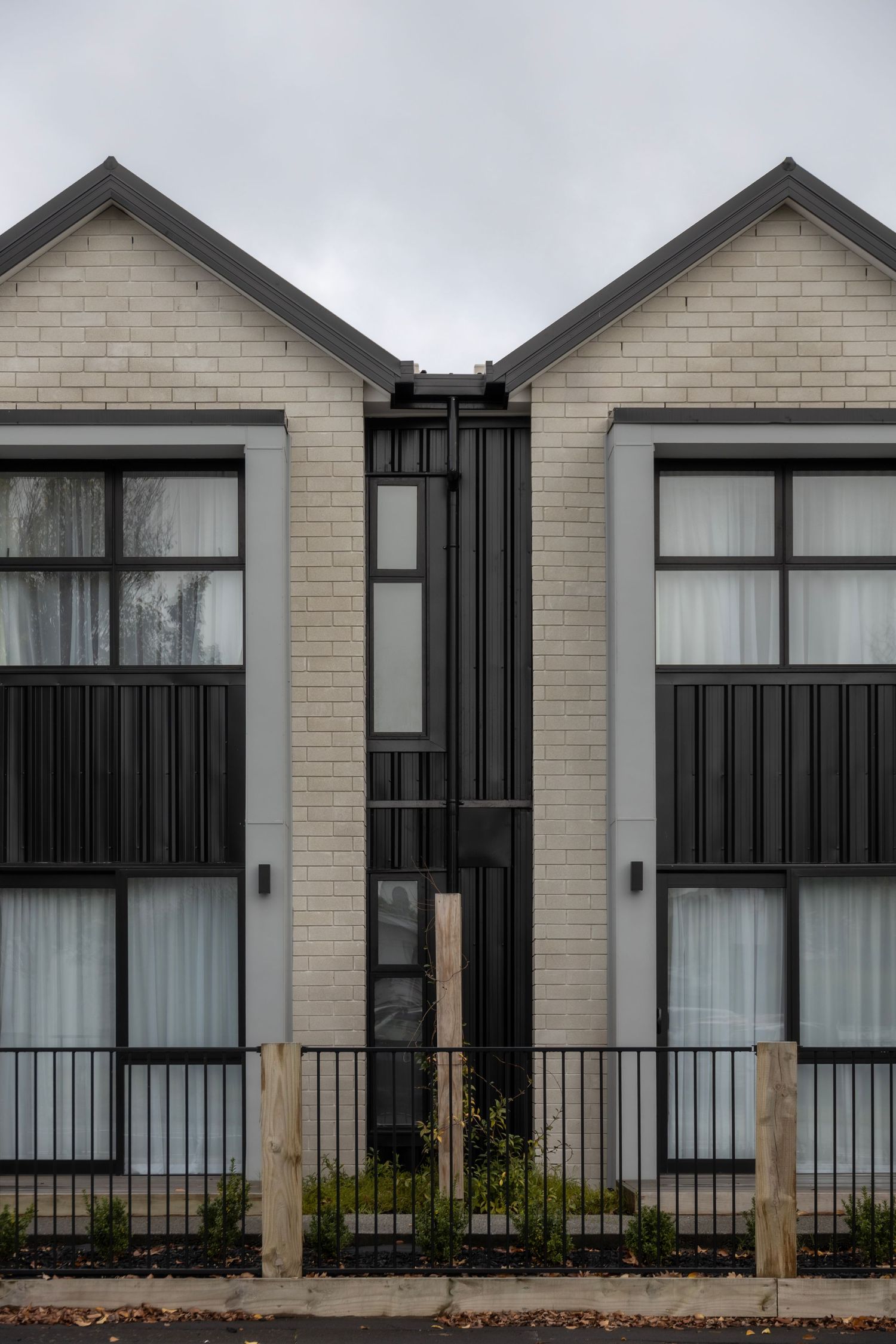 Symmetrical grey brick townhouses with pitched roofs and black accents.