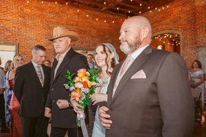 Wedding guests gather in a rustic brick venue decorated with string lights during a reception celebration.
