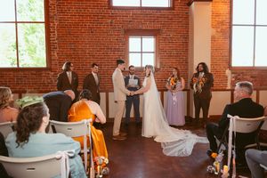 Wedding ceremony in a rustic brick venue with guests watching a couple exchange vows at the altar.
