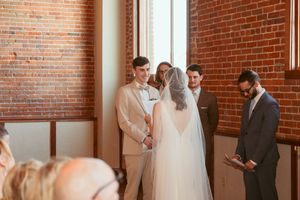 A tender moment unfolds in a loft venue with exposed brick walls as a couple celebrates their first look together.
