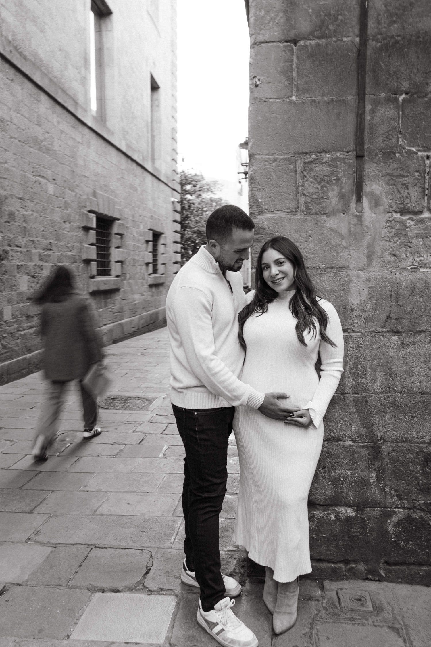 Black and white maternity photos captured in historic stone corridor.