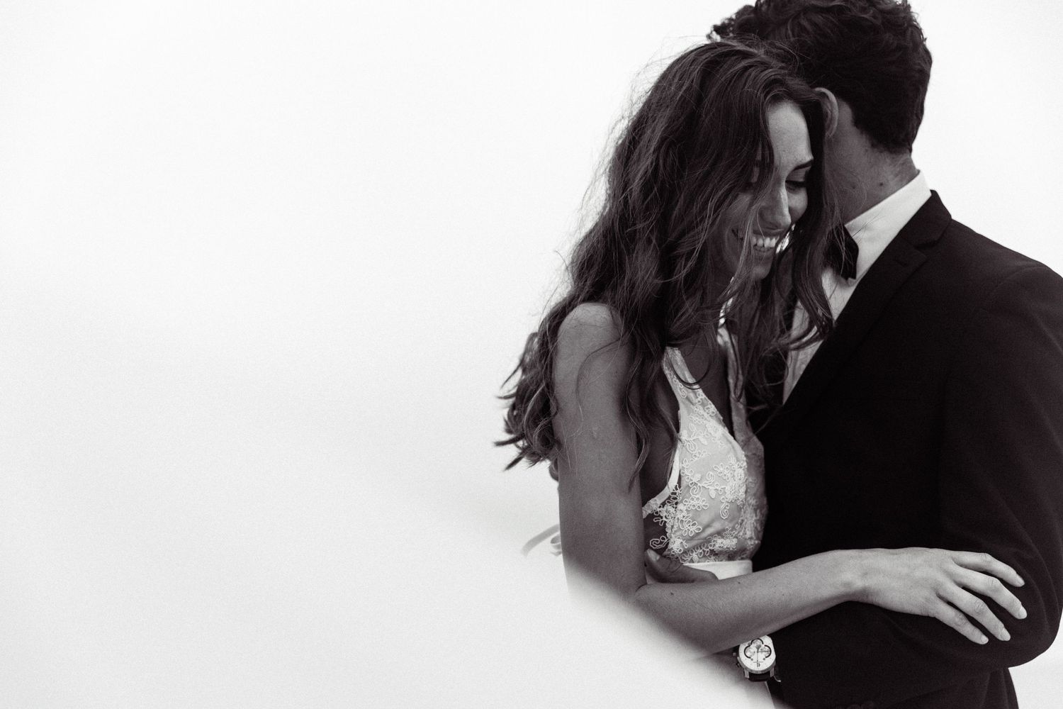 Black and white romantic photos of a couple embracing and kissing in wedding attire at their ceremony.