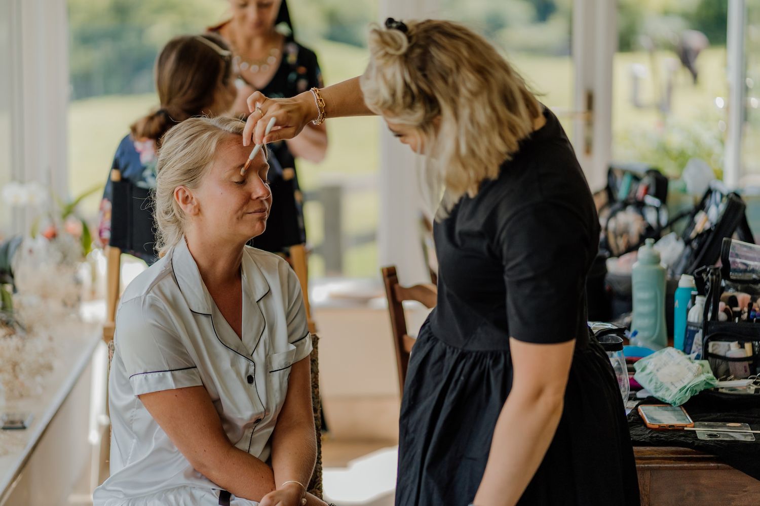 A bright sunlit room where hair and makeup preparations are taking place.