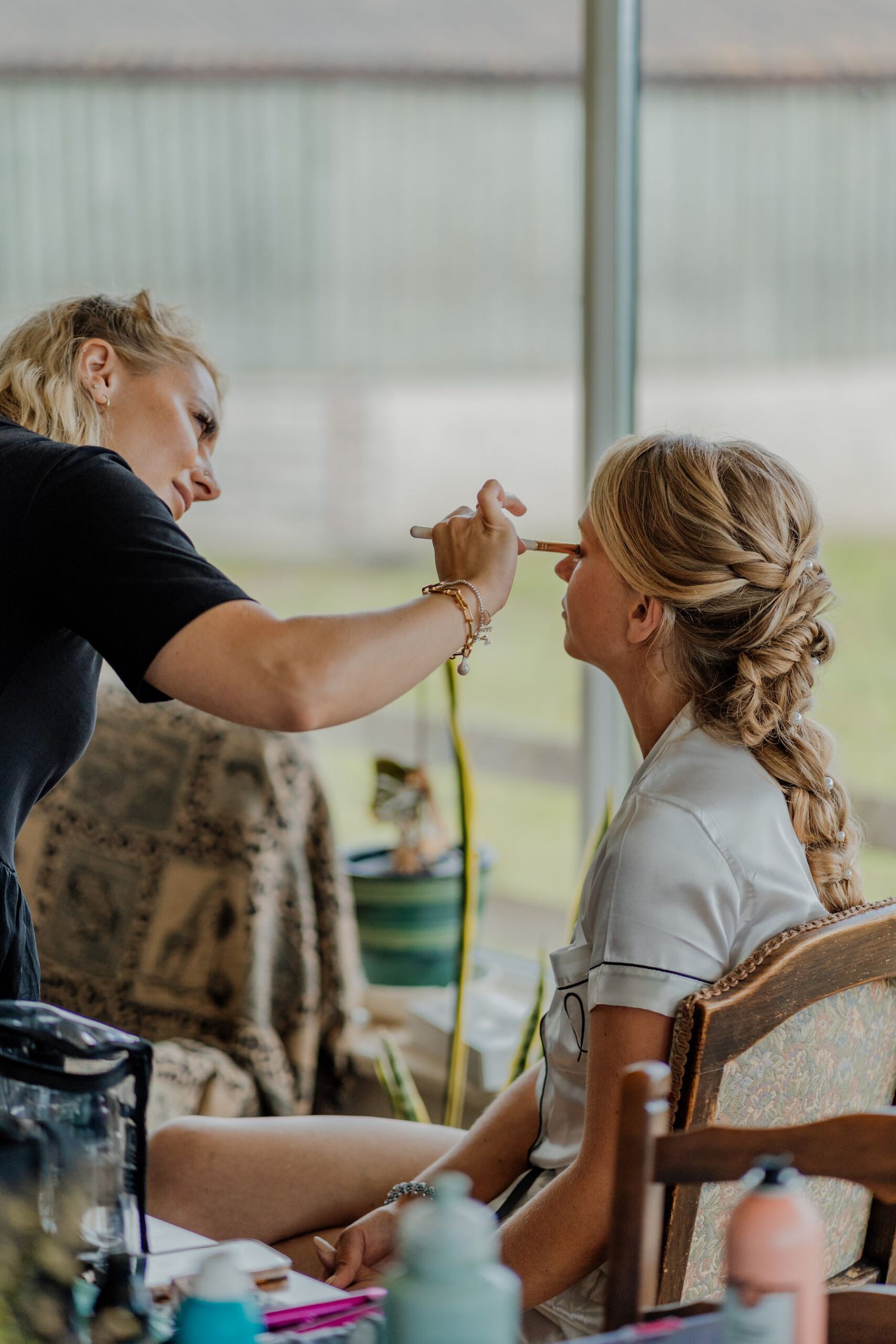Hair styling session in progress by a window with natural lighting.