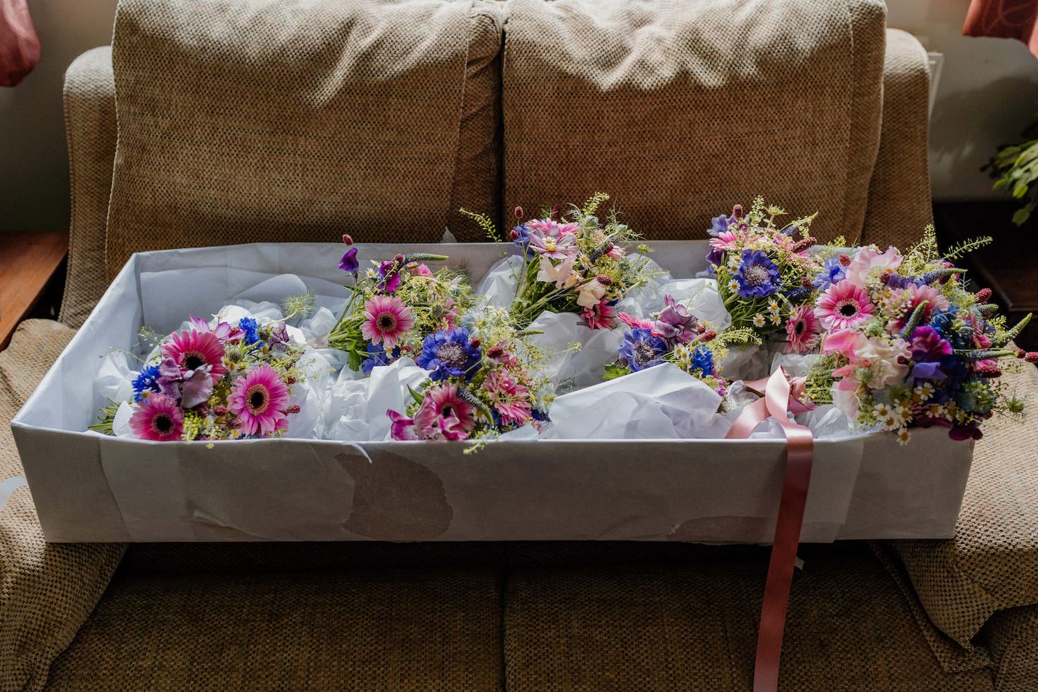 Delicate floral arrangements with pink and purple blooms displayed in white boxes.