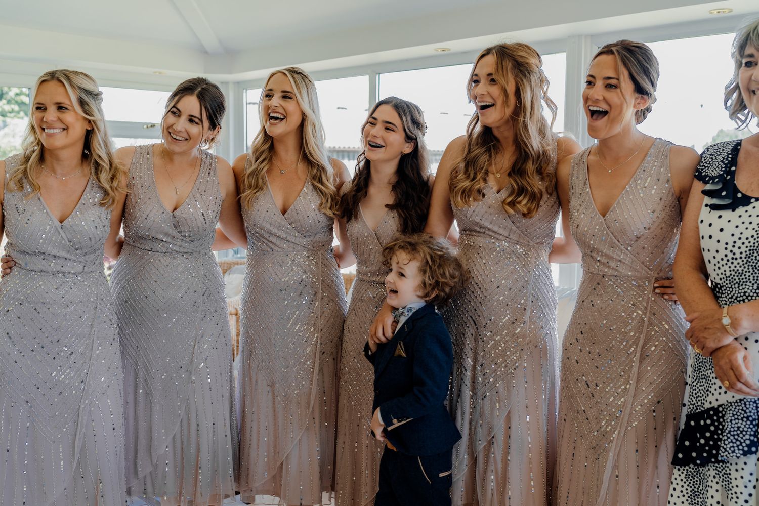 Bridesmaids wearing coordinated silvery gray dresses standing together in a row.