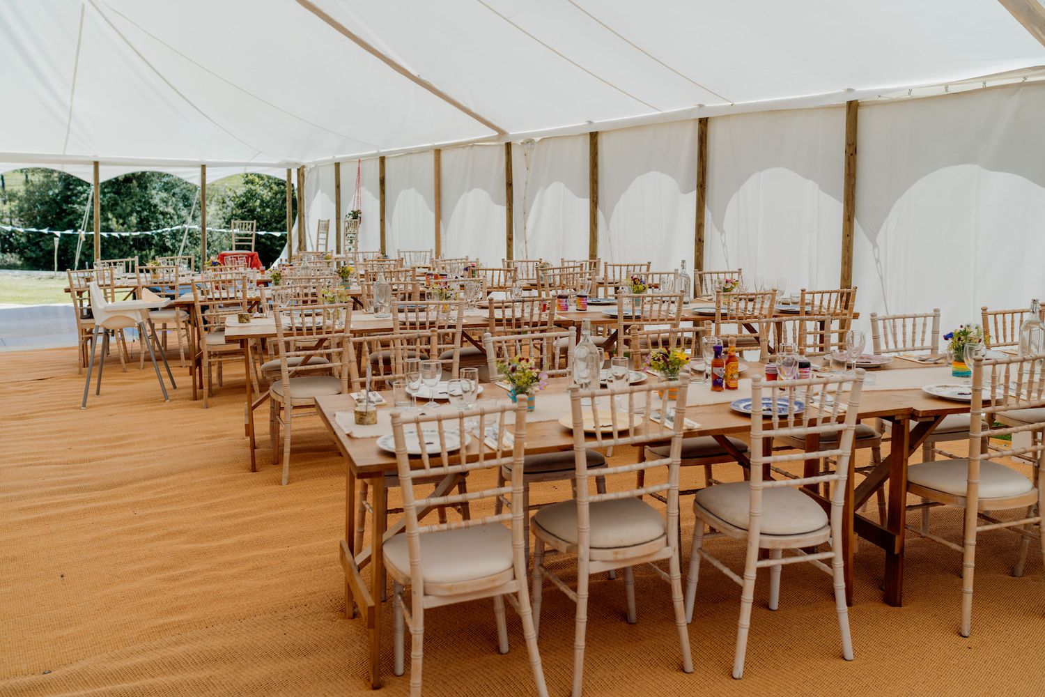 Wedding reception tent interior with wooden floors and elegant table settings.