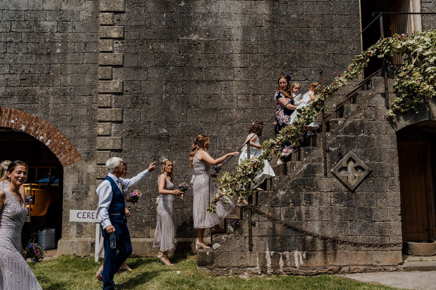 Wedding party posing on stone steps of a historic building during celebrations.