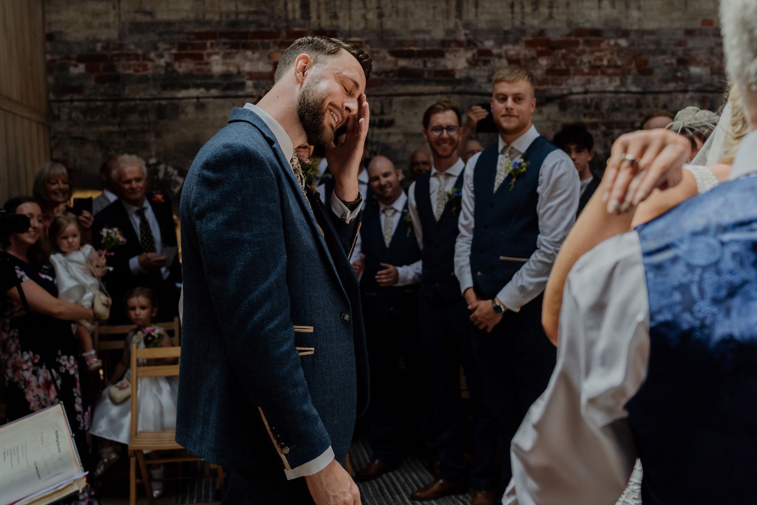 An emotional wedding ceremony moment in a rustic indoor venue.