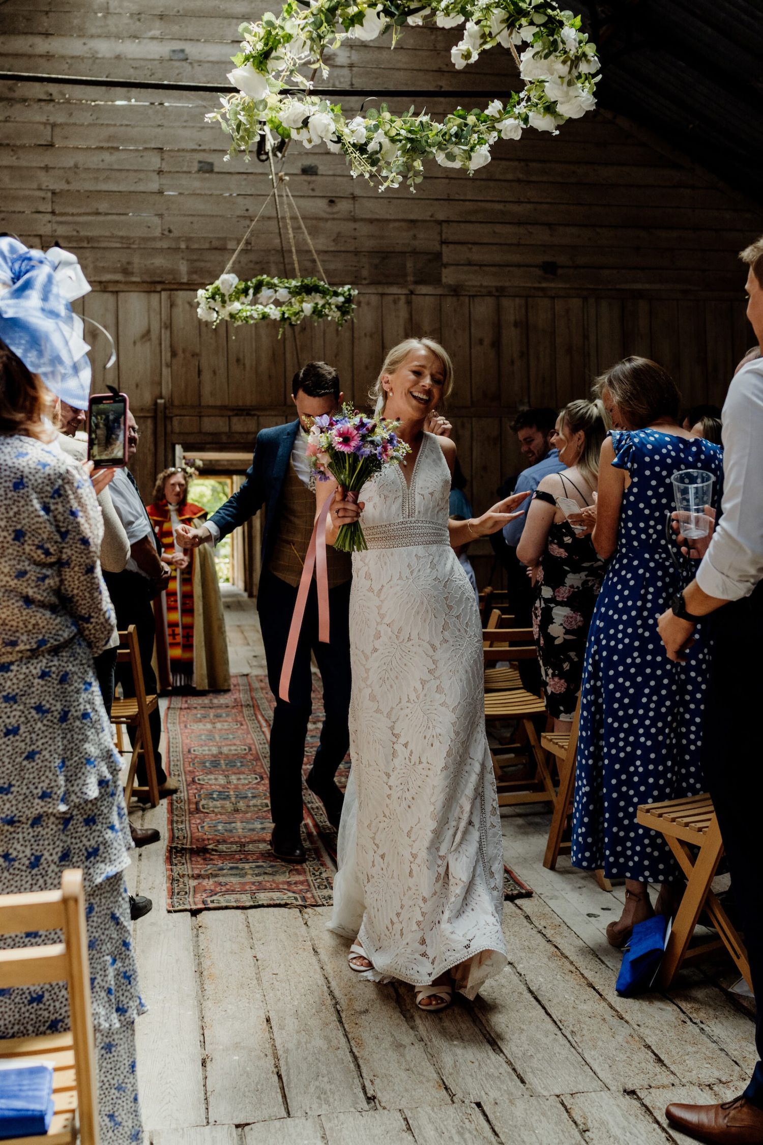A celebration moment in a barn wedding venue with floral decorations overhead.