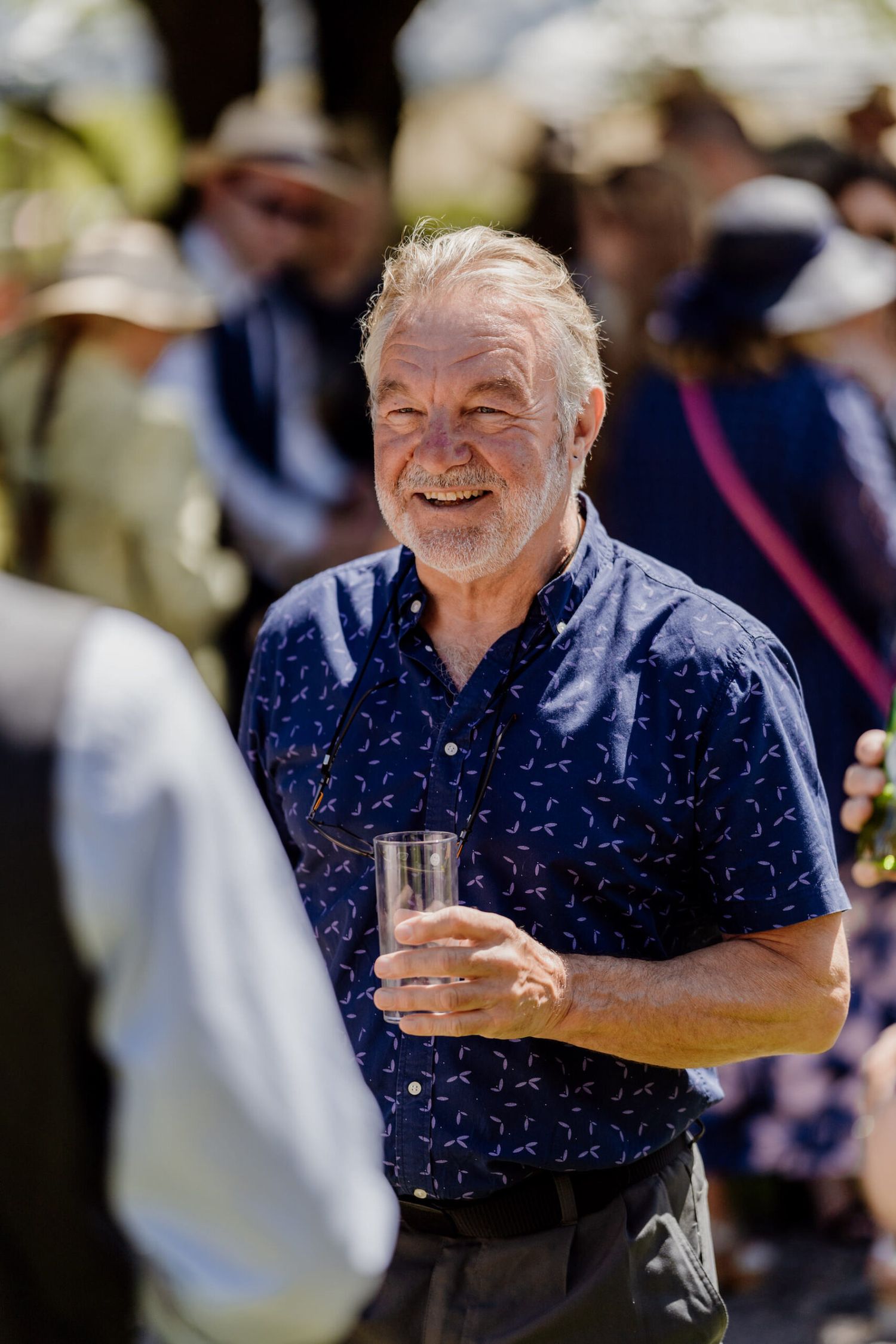 Guest enjoying drinks at outdoor wedding reception wearing navy patterned shirt.