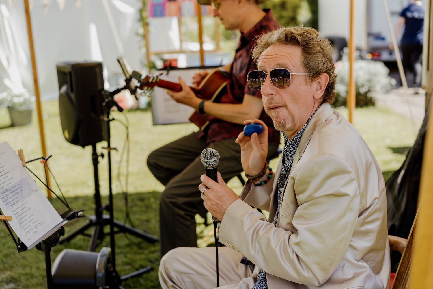 Musicians performing at an outdoor wedding reception under a white tent.