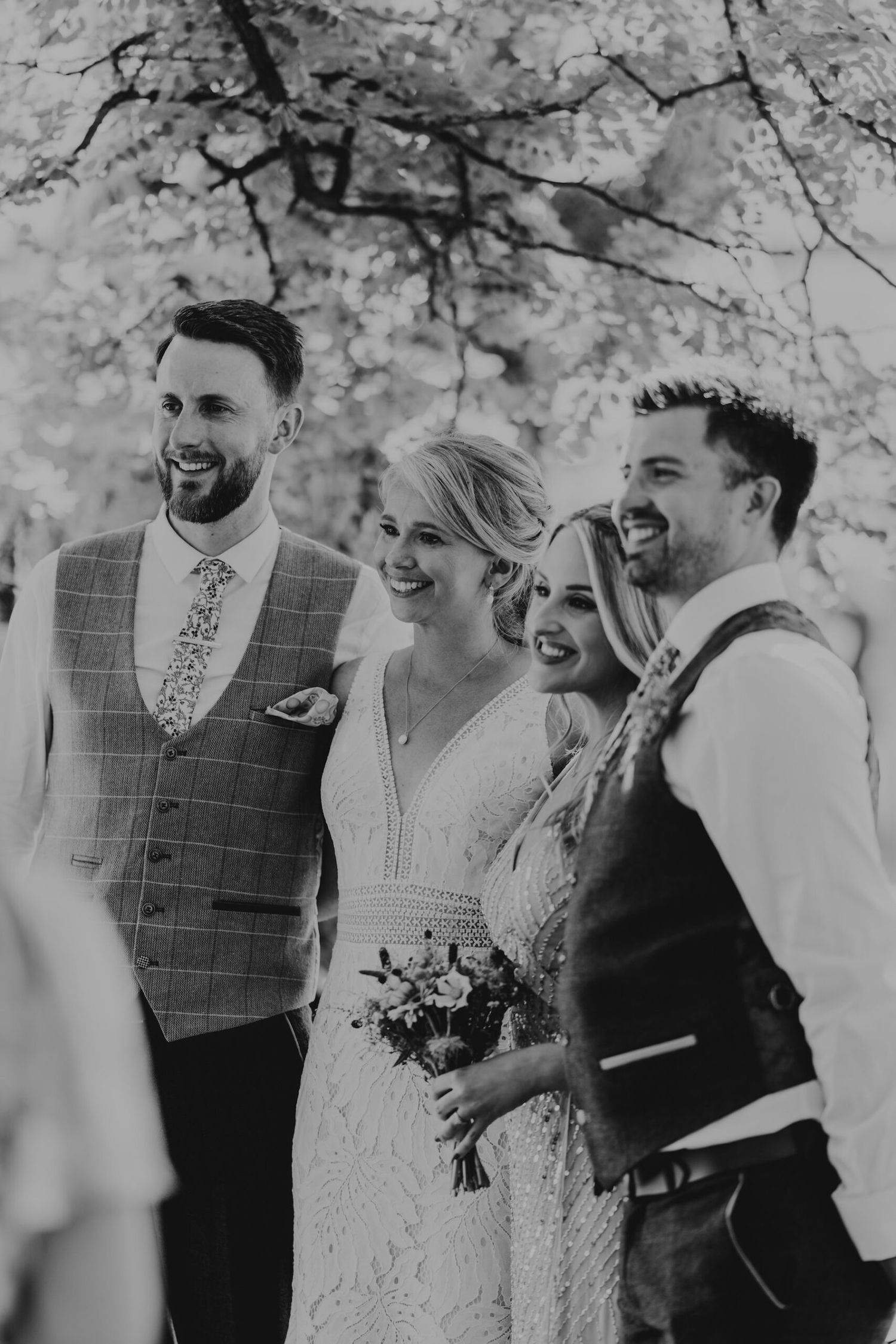 Black and white photo capturing joyful laughter during an outdoor celebration.