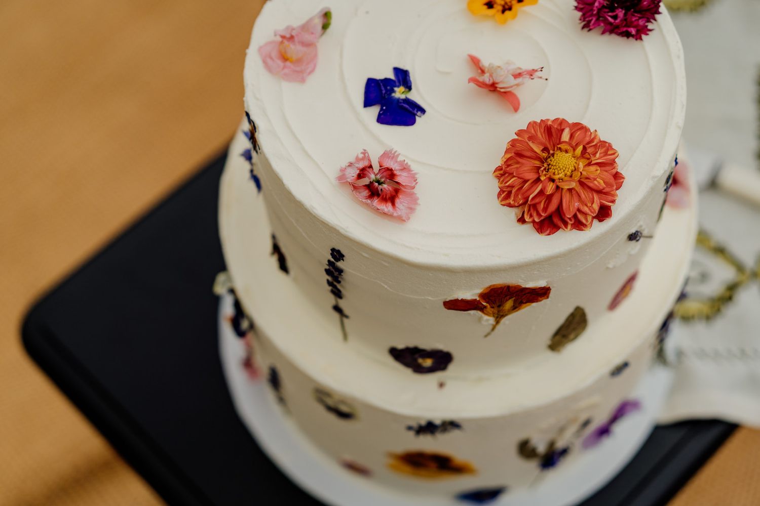 Wedding cake decorated with delicate edible flowers in pink, purple and yellow.