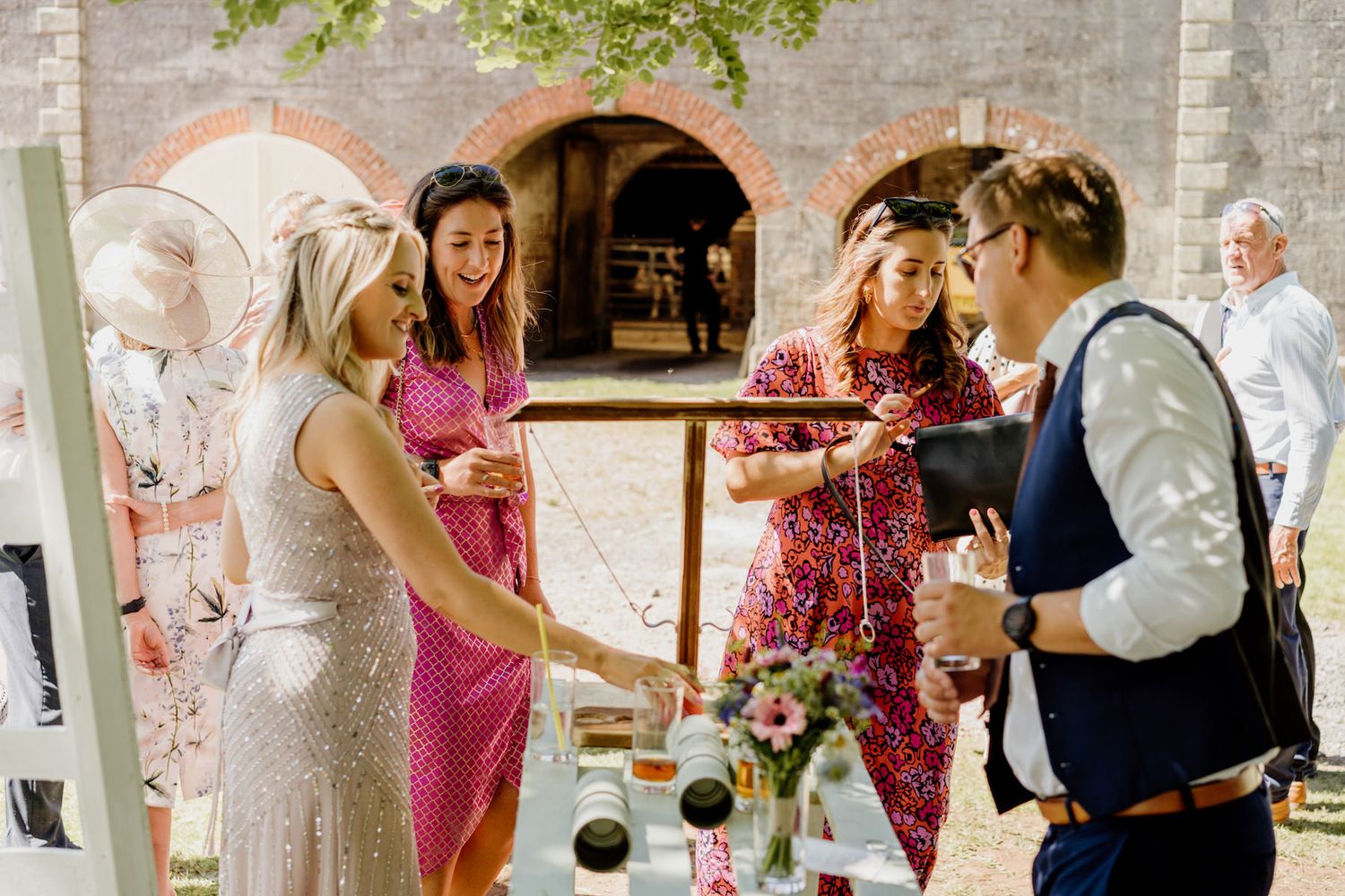 Guests mingling and celebrating at an outdoor reception near a stone building.