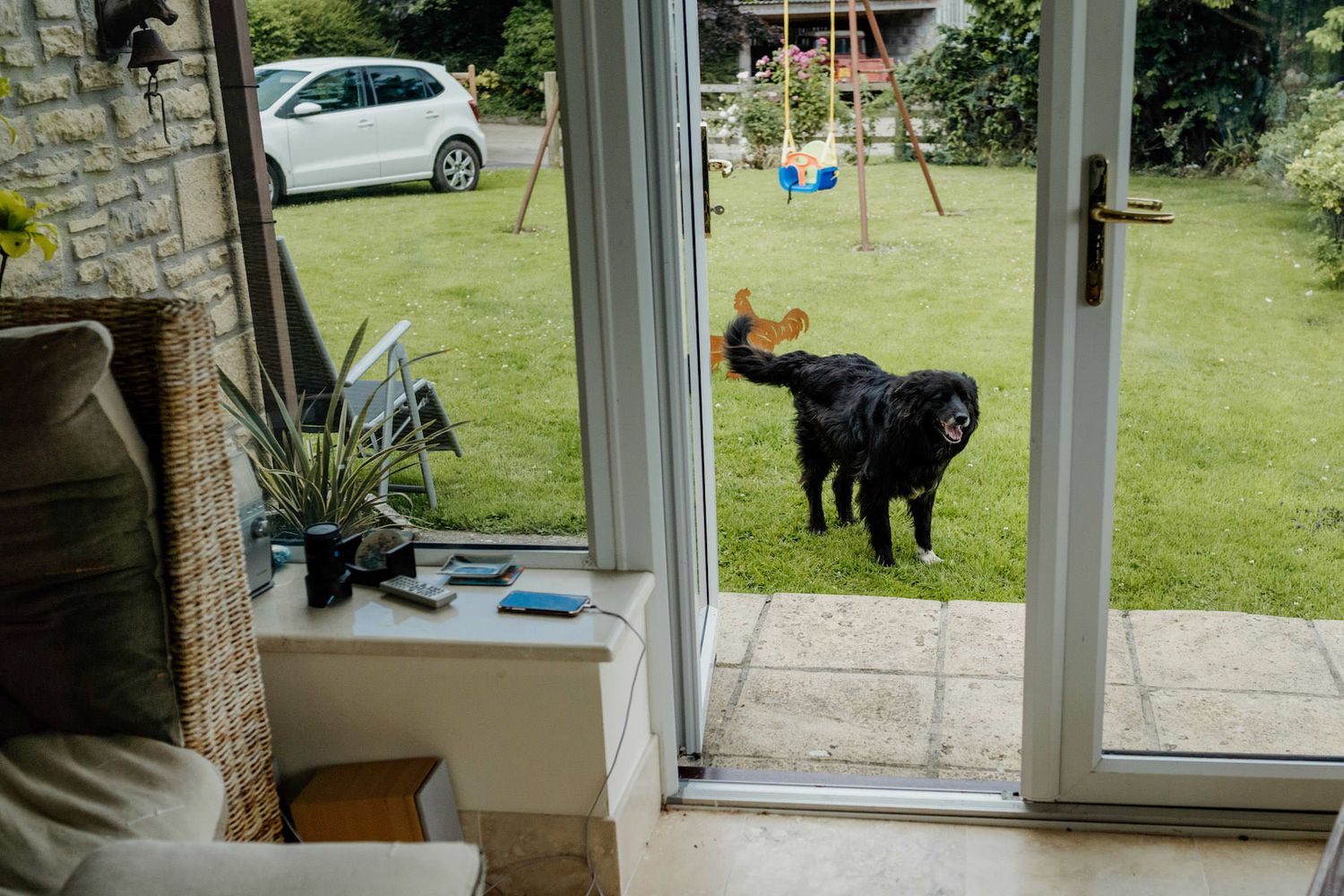 A conservatory-style room with large windows showing a green garden and parked car outside.