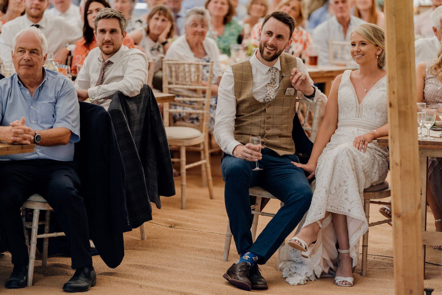 Wedding guests enjoying speeches and entertainment during an indoor reception.