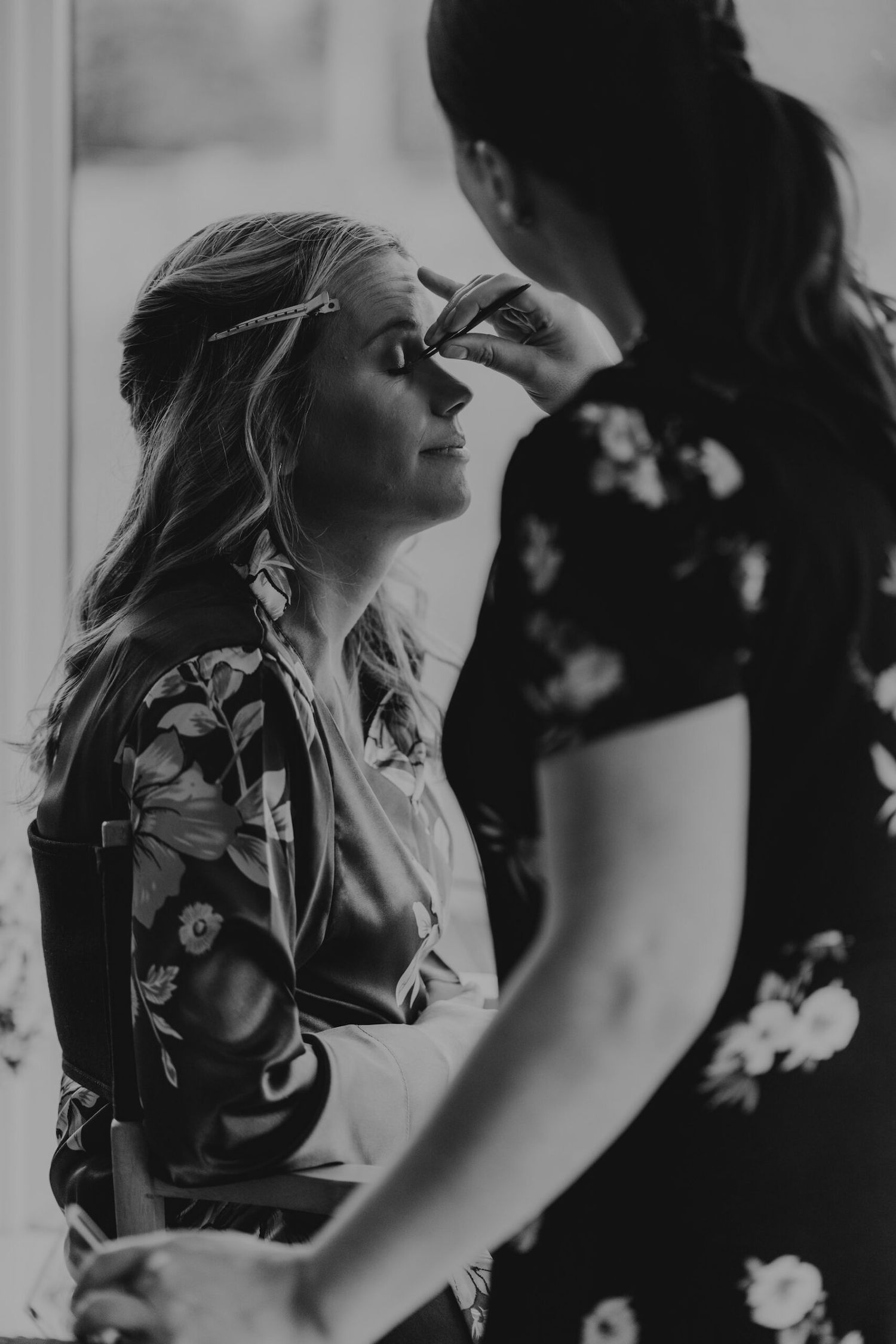 Black and white photo of someone getting their hair styled in a relaxed setting.
