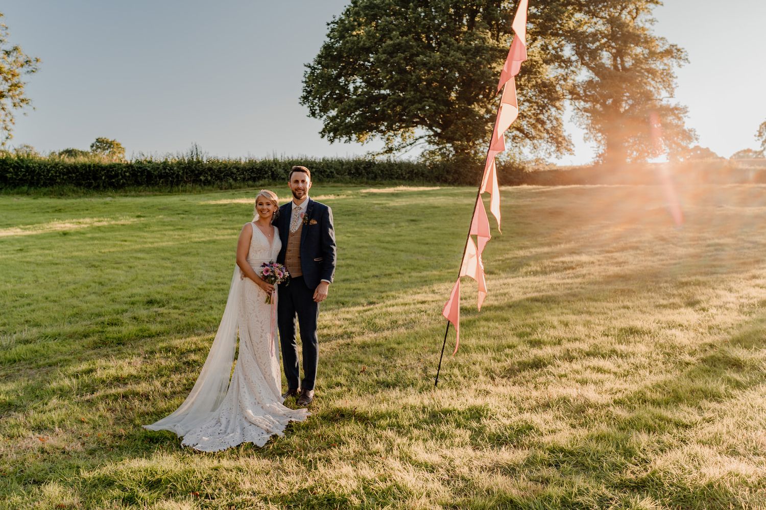 Romantic wedding portraits at golden hour in countryside setting.