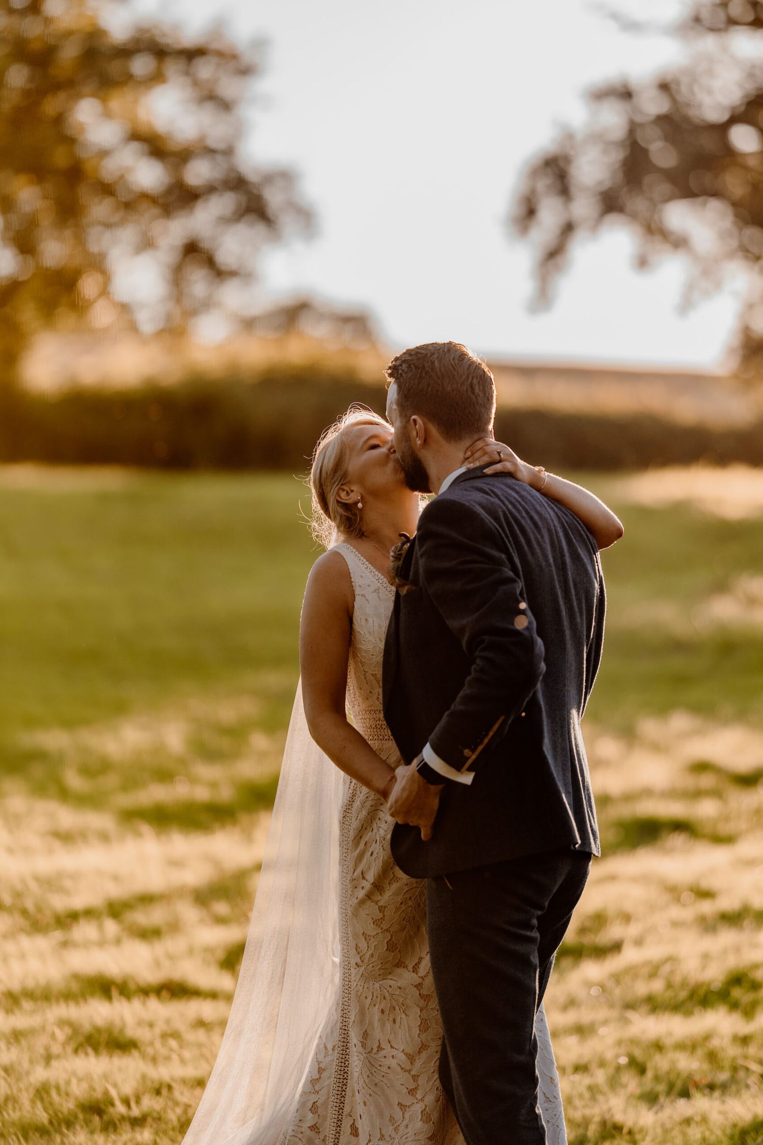 Romantic sunset moment between newlyweds in a grassy field.