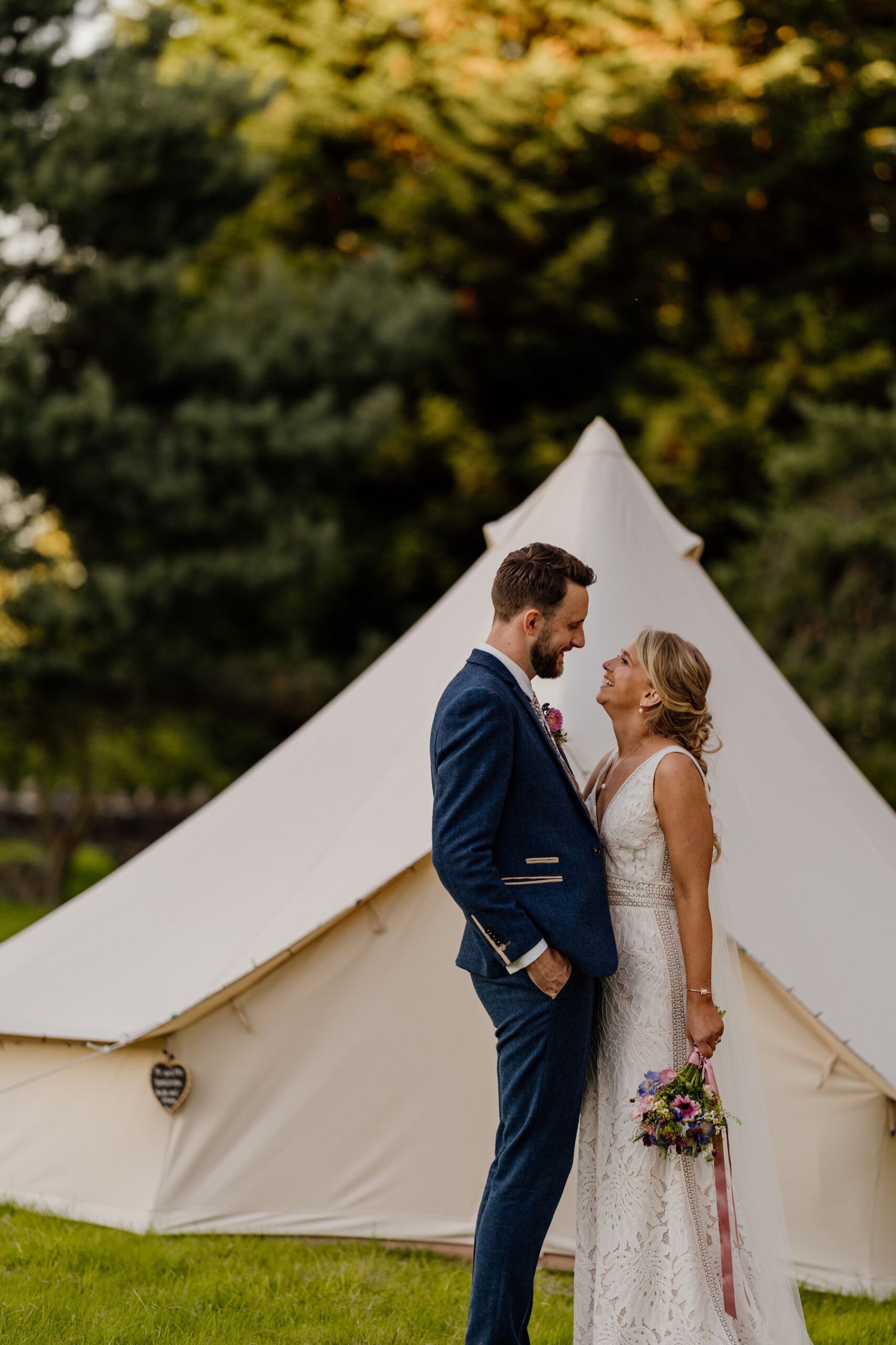 Wedding couple sharing intimate moment in front of white bell tents.