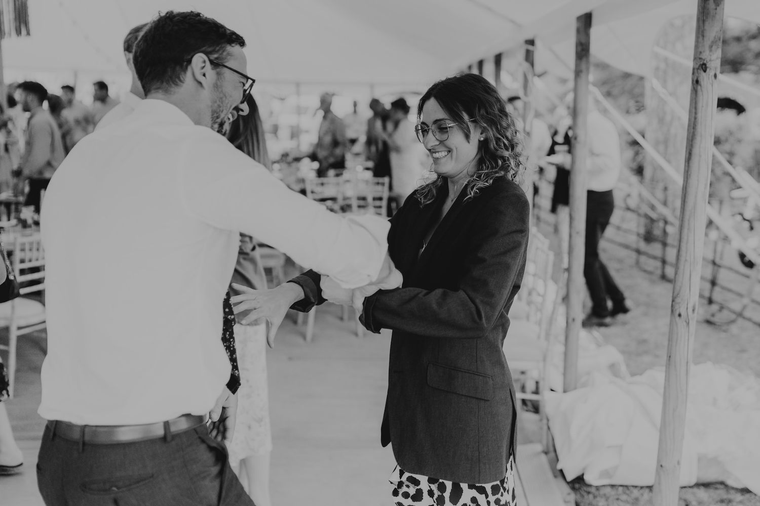Wedding reception guests dancing and celebrating under an indoor venue with string lights.