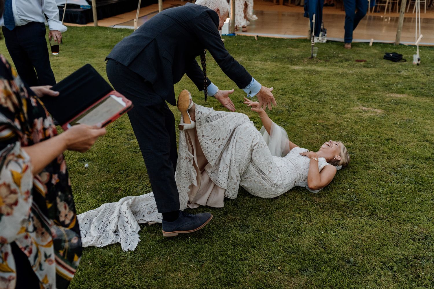 Casual reception scene with guests lounging on blankets in the grass during an outdoor wedding.
