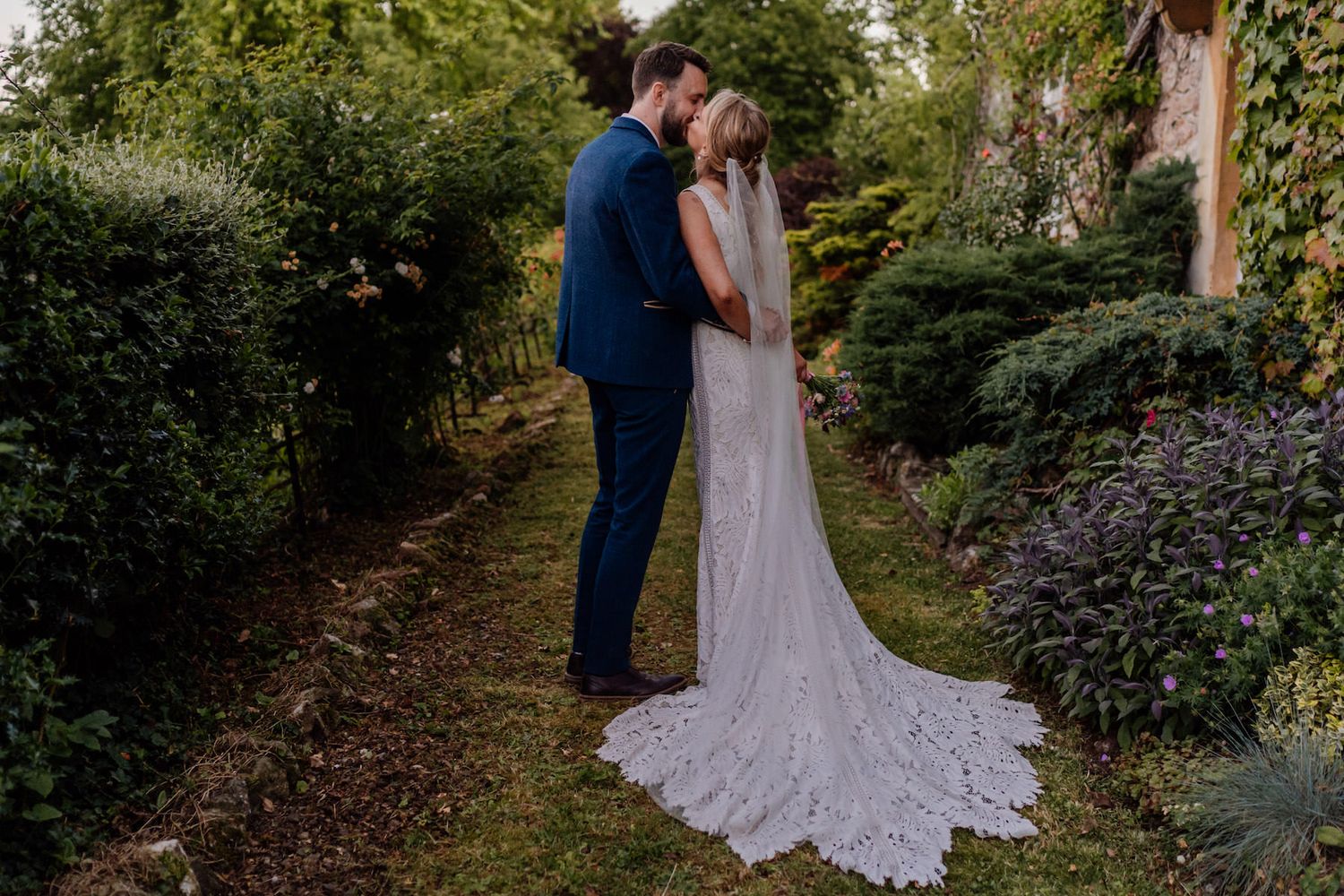 Garden wedding photo session with bride and groom among lush greenery and flowers.