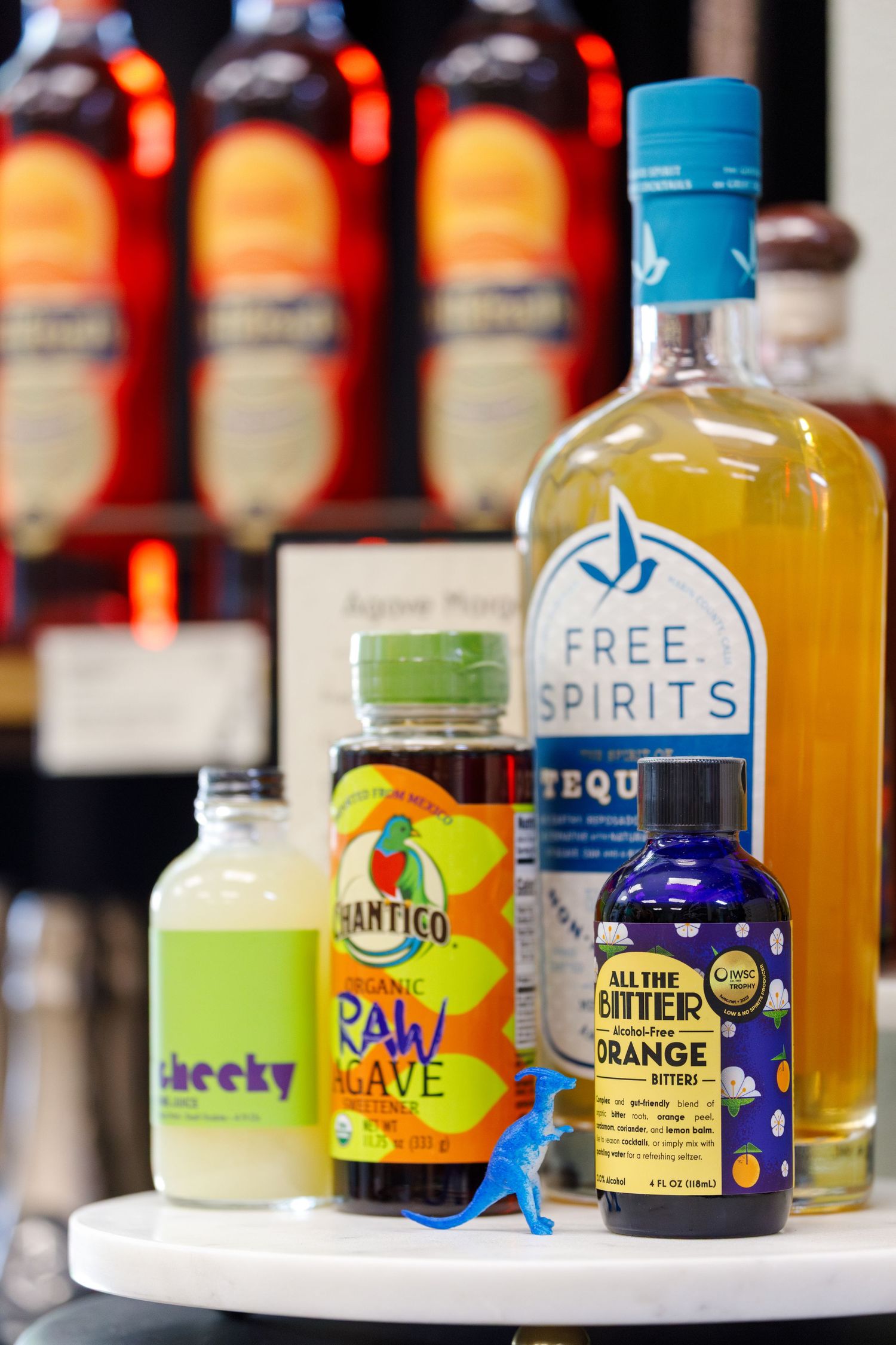 Colorful collection of craft cocktail mixers and spirits including Free Spirits, Raw Wave, and orange bitters on display.