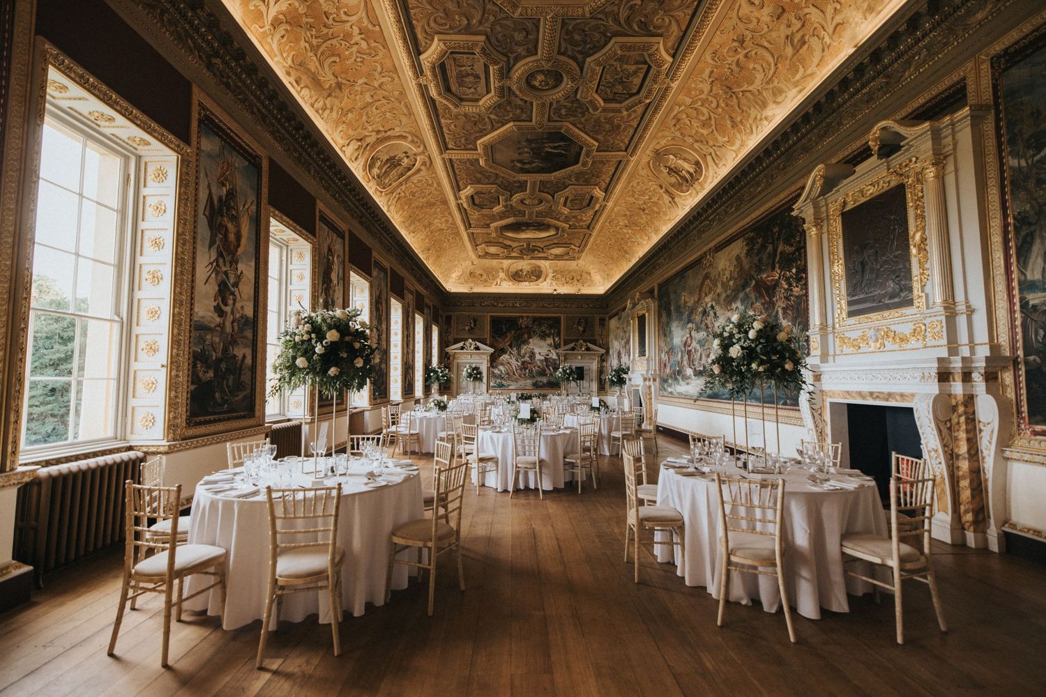 Panoramic view of an ornate baroque ballroom set up for a wedding reception with white tables and elegant decor at Stowe House.