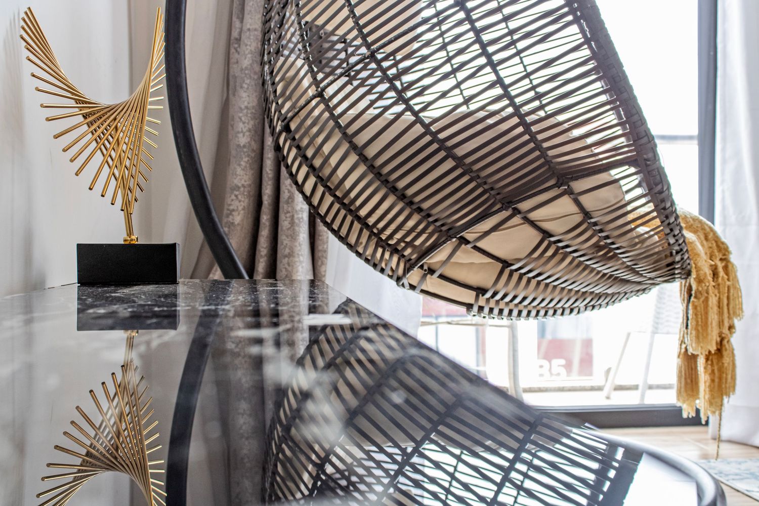 Decorative metallic hanging pendant lamps with bird-like designs and feather accents in a modern interior space.