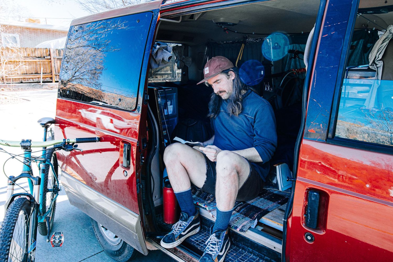 Inside view of a red van with a bike mounted outside while someone sits in the middle row.