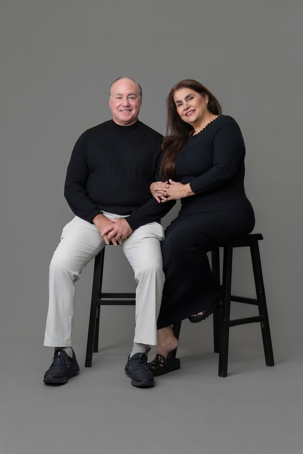 Studio portrait series showing two people seated on black chairs against gray backdrop in various intimate poses.
